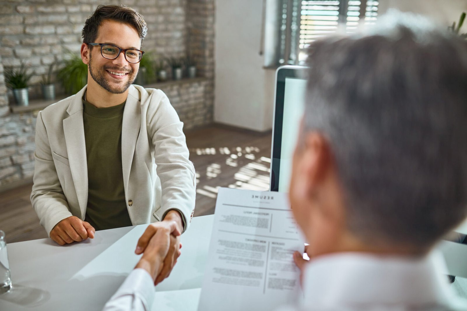 Happy male candidate greeting a member of human resource team on a job interview in the office.